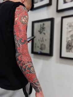 a man with a red and black tattoo on his arm is looking at a tablet