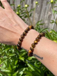 Tiger's Eye Beaded Bracelet 8mm round beads Tiger's Eye, a crystal with glowing bands of yellow golden hues that brings strength and will power! A stone of protection, Tiger's Eye is believed to be watching over its' people and 'keep an eye open' for them!  Approx. 7inches around/ The bracelets are stretchy and fits most peoples' wrists.  Also sometimes referred as Tiger's Eye, Tiger Eye, Cat's Eye. This listing for one (1) Tiger's Eye stretchy bracelet. Thank you for checking out this listing! This treasure helps support my small business and my mission to recycle and reduce waste in our city! Orders over $35 get FREE shipping! To stay updated with new items follow us on Instagram @Tumbledshop  OR Click the link below!  https://www.instagram.com/tumbledshop/ Tigers Eye Bracelet Men, Adjustable Spiritual Crystal Bracelet With Polished Beads, Spiritual Brown Crystal Bracelet With 8mm Beads, Spiritual Hand-strung Evil Eye Bracelet For Healing, Spiritual 8mm Beads Wristband For Healing, Brown Gemstone Beads Crystal Bracelet For Healing, Spiritual Healing Evil Eye Bracelet With Round Beads, Brown Crystal Bracelet With Gemstone Beads For Healing, Spiritual Beaded Evil Eye Bracelet For Healing