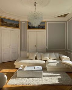 a large white couch sitting in a living room under a chandelier