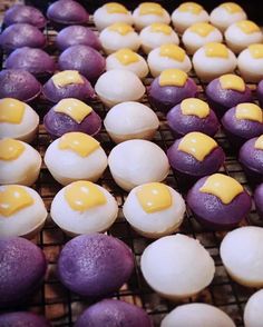 purple and white desserts with yellow icing on cooling racks