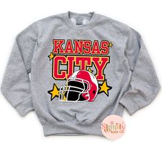 Youth Kansas City Sweatshirt, Kansas City Football Sweatshirt for Kids, Kansas City Shirt, Kansas City Gift, KC Football Crewneck Sweatshirt HOW TO ORDER: Select size from drop down menu Select shirt color from drop down menu Choose quantity MATERIALS:  Printed in shop with DTF (Direct to Film) and then pressed onto shirt. If unsure or in between sizing, I always recommend sizing up!!   Youth sweatshirt Gildan or Jerzee brand depending on stock. Unisex sizing, please refer to size chart  SHIPPING: I will do my best to process your order in a timely manner. I process them in the order I get them. Current processing time is 5-7 days. I use USPS shipping with tracking.  I will not be held responsible for any lost, damaged, or delayed packages once they are shipped out. If an item shows delive Winter Team Spirit T-shirt With Graphic Print, Winter Team Spirit Graphic T-shirt, Winter Fan Gear Graphic T-shirt, Winter Fan Apparel T-shirt With Logo Print, Football Crewneck, City Sweatshirt, Kc Football, Kansas City Football, Football Sweatshirt