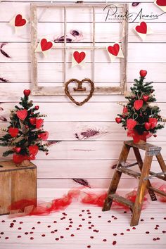 two small christmas trees in front of a window with hearts hanging on the windowsill