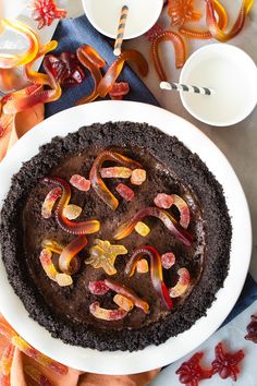 there is a chocolate cake with worms on it and candy in the bowl next to it