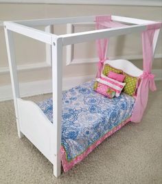 a white bed with pink curtains and pillows on it's sides, in a room