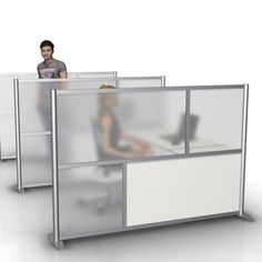 an office cubicle with two people sitting at desks and one person standing in the background