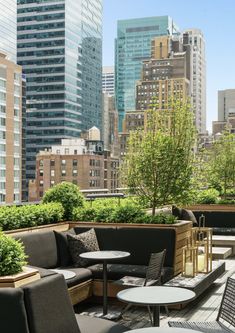 an outdoor seating area on the roof of a building with city buildings in the background