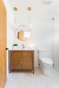 a white bathroom with a wooden cabinet and mirror on the wall next to a toilet