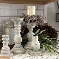 three white candlesticks sitting on top of a table next to a potted plant