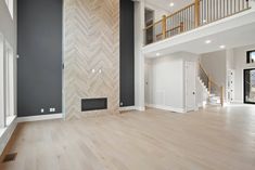 an empty living room with hardwood floors and white walls, stairs to the second floor