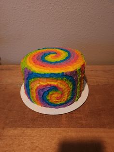 a multicolored cake sitting on top of a wooden table