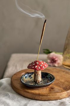 a small red mushroom sitting on top of a wooden plate