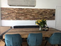 a dining room table with blue chairs and a wood paneled wall in the background