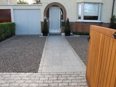 a house with a white front door and brick walkway leading to the entrance area that is lined with hedges