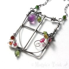 a necklace made out of metal and glass beads on a white surface with a chain attached to it