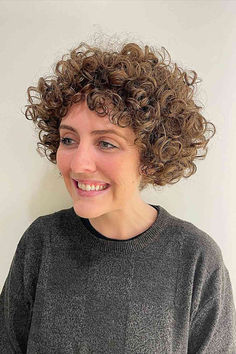 Woman with a jaw-length bob styled into graduated ringlets Curly Jaw Length Hair, Curly Graduated Bob, Graduated Curly Bob Haircut, Graduated Curly Bob, Curly Concave Bob, Wobbly Headed Bob, Graduated Bob