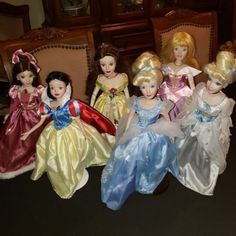 a group of dolls sitting on top of a wooden table next to each other in dresses