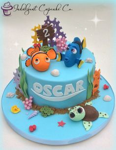 a blue birthday cake decorated with sea animals and under the sea characters on it's side