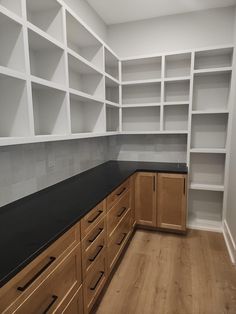 an empty kitchen with white shelving and black counter tops on the counters in front of it