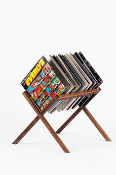 a stack of magazines sitting on top of a wooden stand in front of a white background