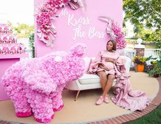 a woman sitting on a white couch next to a pink wall with flowers and an elephant