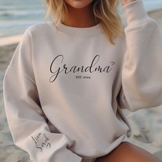 Personalized Grandma Sweatshirt with Grandkids Names on Sleeve, Custom Granny Sweater, Est Custom Date Gramma Sweatshirt, Gift for Grandma Ideal for any situation, a unisex heavy blend crewneck sweatshirt is pure comfort. These garments are made from polyester and cotton. This combination helps designs come out looking fresh and beautiful. The collar is ribbed knit, so it retains its shape even after washing. There are no itchy side seams on these sweaters.  .: Made with a medium-heavy fabric blend of 50% cotton and 50% polyester, this sweatshirt feels cozy and is the perfect choice for those colder months. .: The classic fit along with the crew neckline deliver a comfy wearing experience with a clean-cut style. Meanwhile, the double-needle stitching at the shoulder, armhole, neck, waistba Personalized White Tops For Winter, Personalized Long Sleeve White Tops, Personalized White Long Sleeve Tops, Personalized Casual Crew Neck Tops, Family Matching Long Sleeve Letter Print Tops, Customizable Long Sleeve Tops For Family Matching, White Long Sleeve Sweatshirt For Family Matching, White Sweater With Name Print For Fall, Family Matching White Long Sleeve Sweatshirt