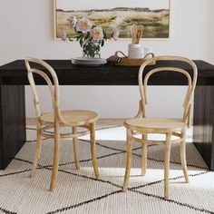 two chairs sitting at a table in front of a painting