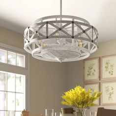 a white chandelier hanging over a dining room table with vases and flowers