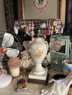 a table topped with lots of assorted items and jewelry next to a framed photo