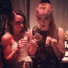 two women are holding drinks and bread in their hands