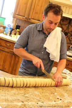 a man is cutting dough on top of a kitchen counter with a large rolling pin