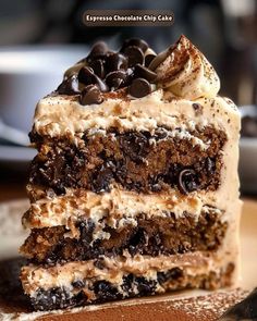 a piece of cake with chocolate chips and cream frosting is on a brown plate