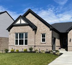 a brick house with grass in front of it and blue skies above the windows on a sunny day