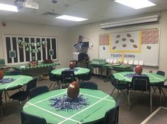 a football themed classroom is decorated with green tablecloths and black chairs for the tables