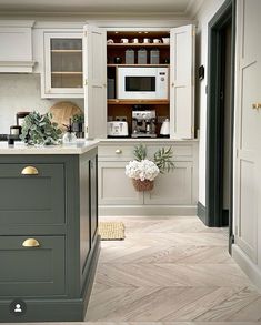 a kitchen with white cabinets and gray counter tops, wood flooring and gold handles