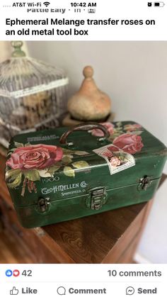 an old metal tool box with roses painted on it is sitting on a wooden table