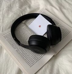 black headphones laying on top of an open book