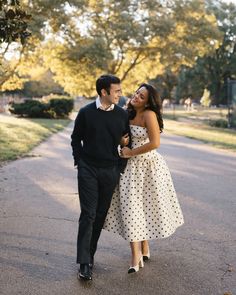 Couple walking arm in arm in park, woman wearing white polka dot dress, man in black sweater Engagement Pic Outfits, Engagement Photos Central Park, Engagement Shoot Outfit Ideas, Central Park Engagement Shoot, Outdoor Engagement Pictures, Outfit Ideas Stylish, Park Engagement Shoot, Winter Engagement Photos Outfits, Classic Couple