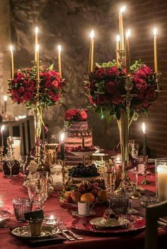 a dining table with candles and flowers in vases on the top is set for a formal dinner