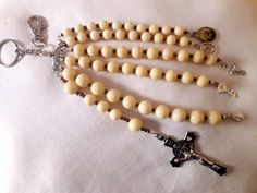 a rosary and keychain with a cross on the front is laying on a white cloth