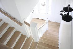 an overhead view of a staircase with white railings and wood flooring, along with two black lights on either side of the stairs