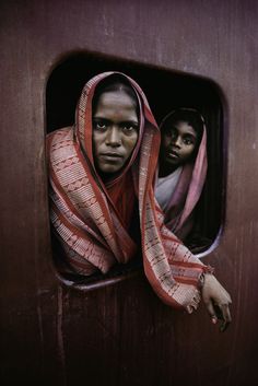 two people looking out the window of a train