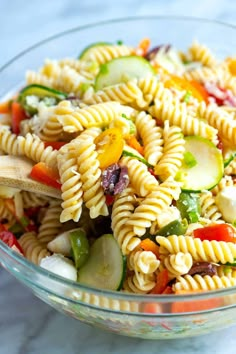 a bowl filled with pasta salad and wooden spoon