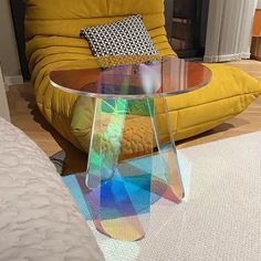 a glass table sitting on top of a wooden floor in front of a yellow couch