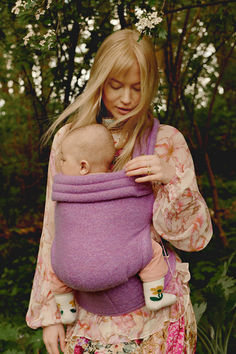 a woman holding a baby in a purple sling