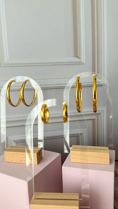 three gold rings and two pink boxes in front of a white wall with a door