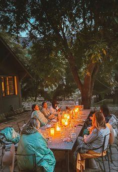 a group of people sitting around a table with candles on it