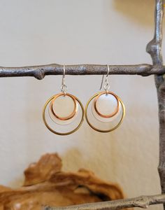 "This is a contemporary geometric earring design. It is made with 3 Semi-precious metals, Sterling, Brass and Copper. These largest ring is Raw Brass, layered with a medium Satin Sterling disc, and finished with a small Raw Copper ring. These three Semiprecious metals create a unique and contemporary earring. 38.00Brass and Copper rings with medium 3/4\" Satin Sterling disc Gift Box Included" Modern White Metal Hoop Earrings, Modern White Earrings For Anniversary, Modern Nickel-free Rose Gold Earrings, Modern Hypoallergenic Rose Gold Earrings, Modern Rose Gold Dangle Earrings, Metal Circle Earrings For Anniversary, Modern White Brass Jewelry, Anniversary Circle Metal Earrings, Modern Metal Earrings For Anniversary