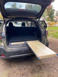 the back end of a car with an open hatchback door and wooden planks