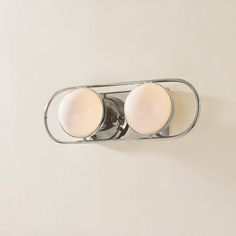 two lights are on the wall in front of a mirror