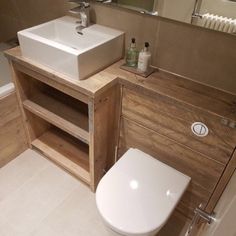 a white toilet sitting next to a wooden sink vanity in a bathroom under a mirror